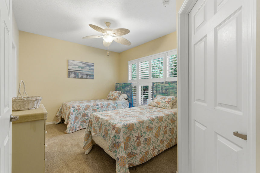 Guest bedroom at 35103 Harbour Vista Cir featuring twin beds, coastal bedding, and white plantation shutters in St. Augustine, FL.