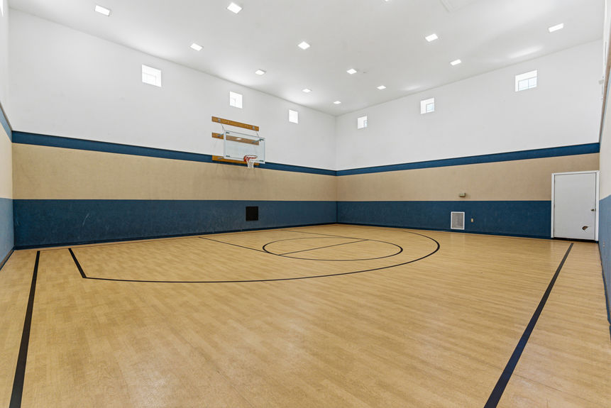 Full-size indoor basketball court with high ceilings and wood flooring at the Harbour Vista Cir complex in St. Augustine, FL.