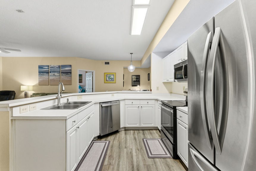 View of the stainless steel refrigerator, oven, and double sink in a St. Augustine, Florida condo kitchen.