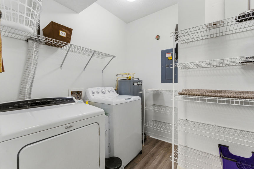 Interior laundry room with washer, dryer, water heater, and wire shelving storage at 35103 Harbour Vista Cir, St. Augustine.