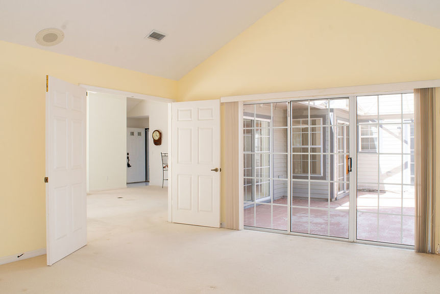 Large primary bedroom at 364 Village Dr, St. Augustine, featuring vaulted ceilings and sliding glass doors that lead to a private, screened-in sunroom within the gated Villages of Vilano community.