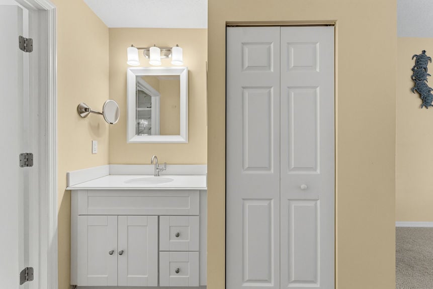 Modernized bathroom at 35103 Harbour Vista Cir featuring a walk-in glass-enclosed shower with marble-style tile, a white vanity, and nautical sea turtle artwork in St. Augustine, FL.