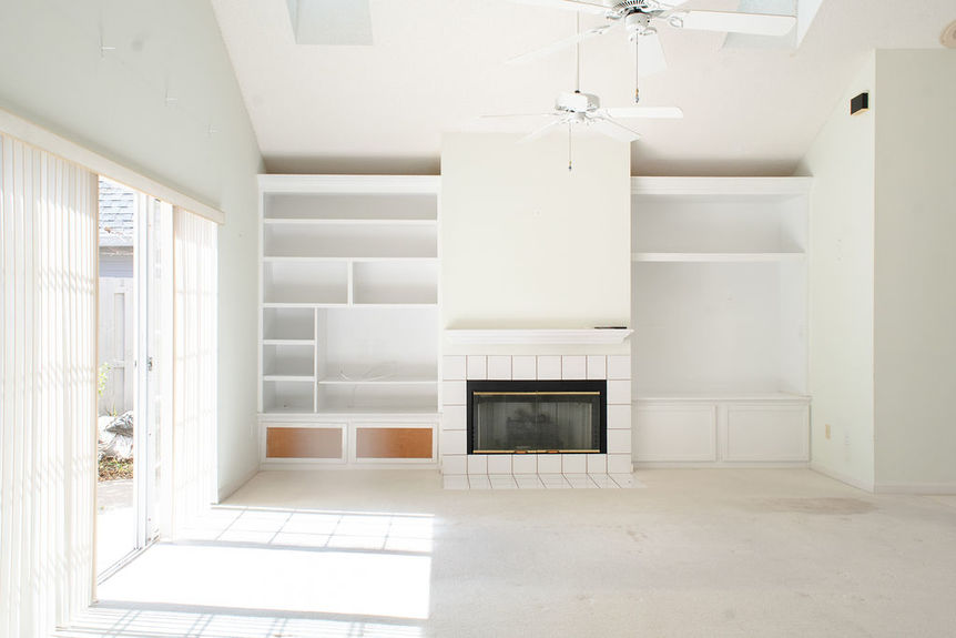 Spacious living room at 364 Village Dr with vaulted ceilings, skylights, white tile fireplace, and built-in shelving overlooking marsh views in Villages of Vilano.