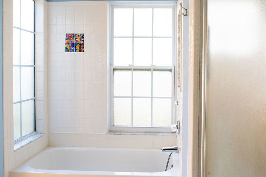 A bright bathroom at 364 Village Dr featuring a white tile tub surround with decorative accents and a large window for natural light.