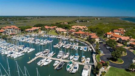 Aerial view of a luxury marina in St. Augustine, Florida, featuring sailboats, yachts, and Mediterranean-style condos surrounded by coastal marshlands—ideal for those relocating for a nautical lifestyle.