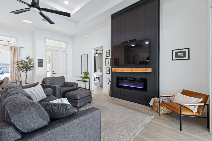 View from the living room toward the entryway and primary bedroom hall, showing LVP flooring and black shiplap architectural details.