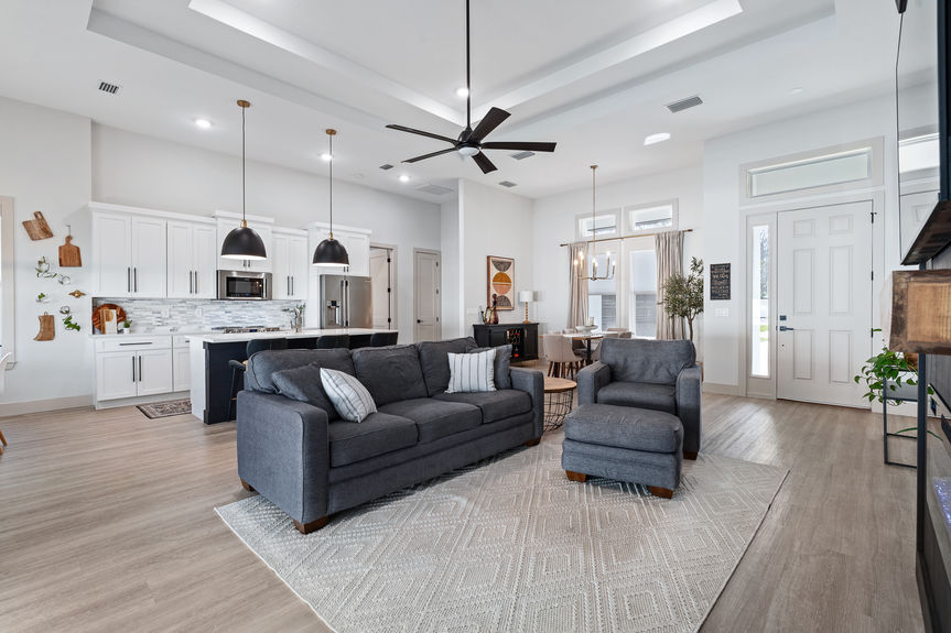 View from the living room toward the entryway and primary bedroom hall, showing LVP flooring and black shiplap architectural details.