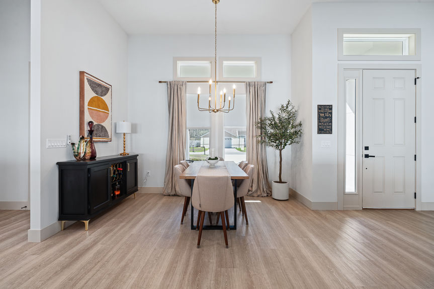 Centered view of a modern dining room featuring a gold candelabra chandelier, neutral tones, and luxury vinyl plank flooring.