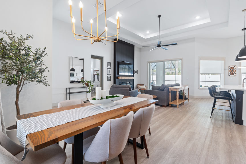 View from the dining table across the great room to the fireplace and pool area, highlighting the expansive 12-foot ceilings.