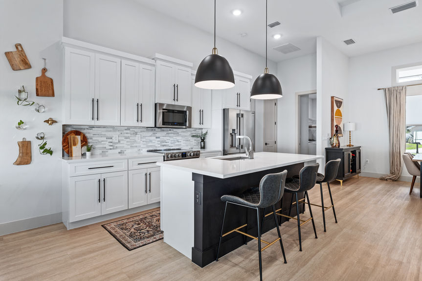 Modern kitchen with white shaker cabinets, a black center island with barstools, and contemporary pendant lighting in a Palm Coast home.