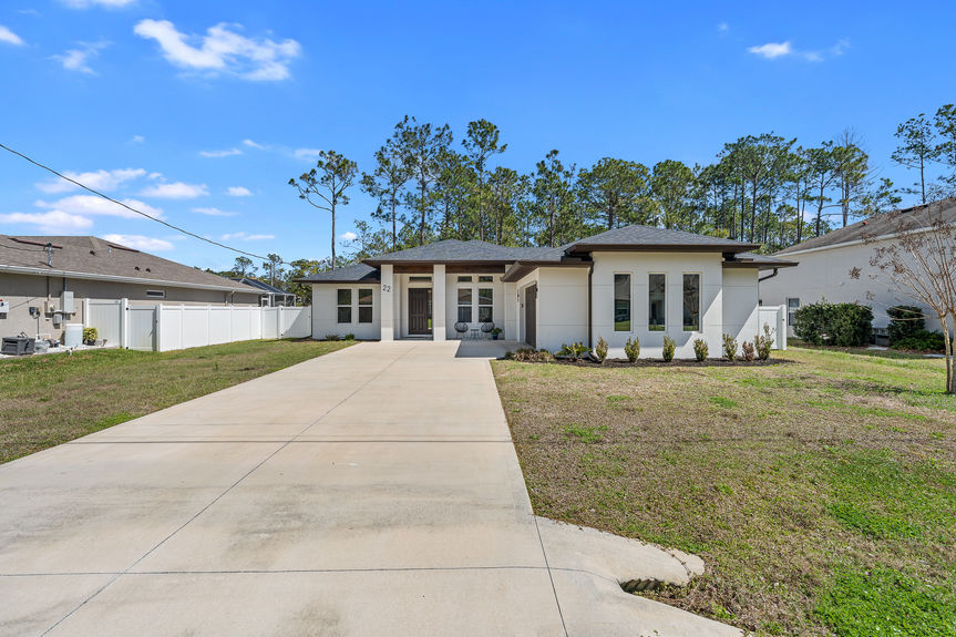 Front exterior view of a contemporary Florida ranch home featuring a white facade, dark trim, and professional landscaping.
