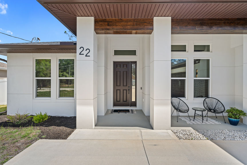 Architectural detail of the front entrance showing the house number 22, modern white pillars, and a dark wood-stained ceiling beam.