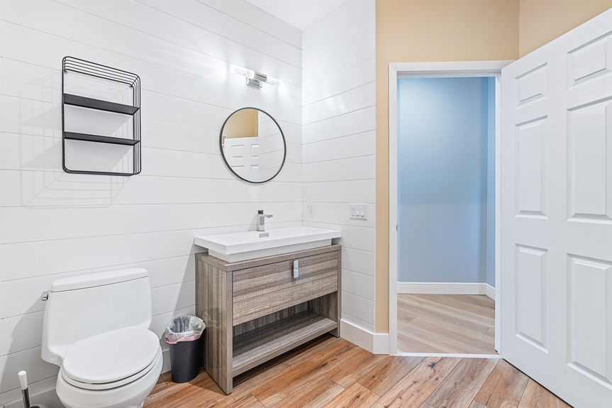 Renovated bathroom featuring a dark wood vanity, white marble countertop, and a modern LED-backlit mirror.