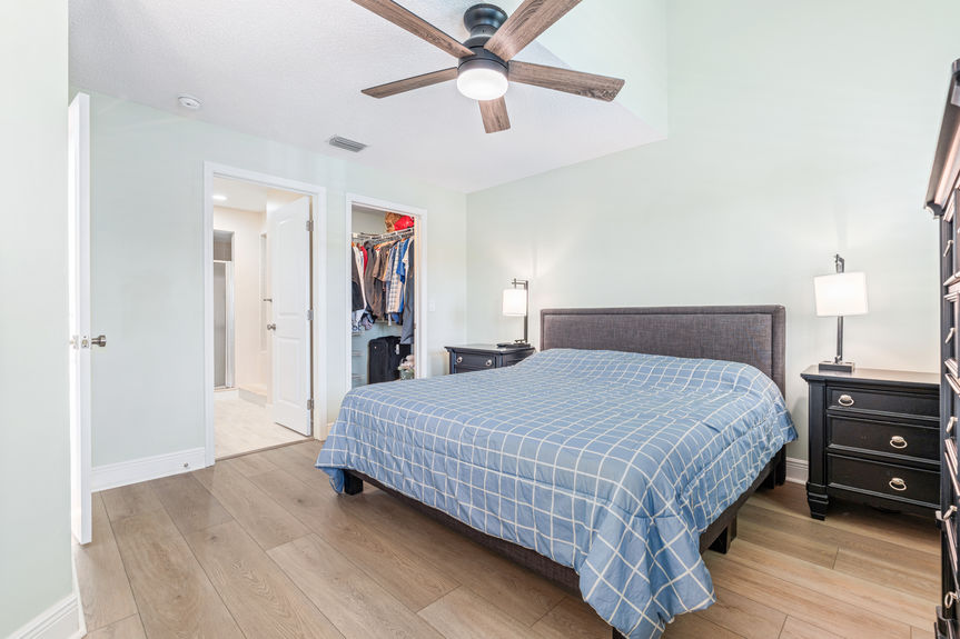 Master bedroom showing a dark wood dresser and bed frame with white plantation shutters and new flooring at 37 Captains Walk.