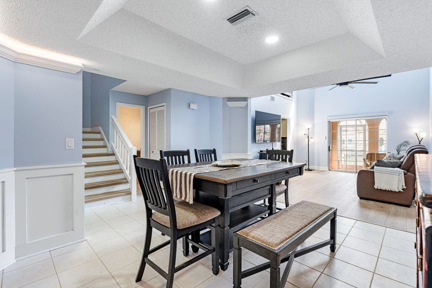 Interior view of the dining area with wainscoting and a dark wood table, looking toward the living room and staircase.