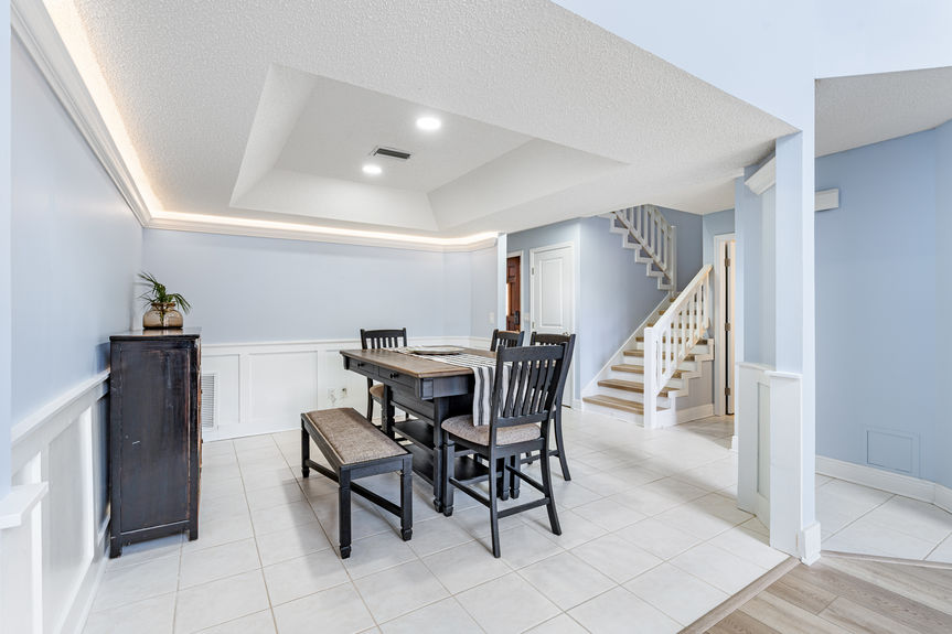 Interior view of the dining area with wainscoting and a dark wood table, looking toward the living room and staircase.