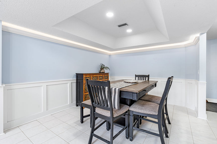 Interior view of the dining area with wainscoting and a dark wood table, looking toward the living room and staircase.