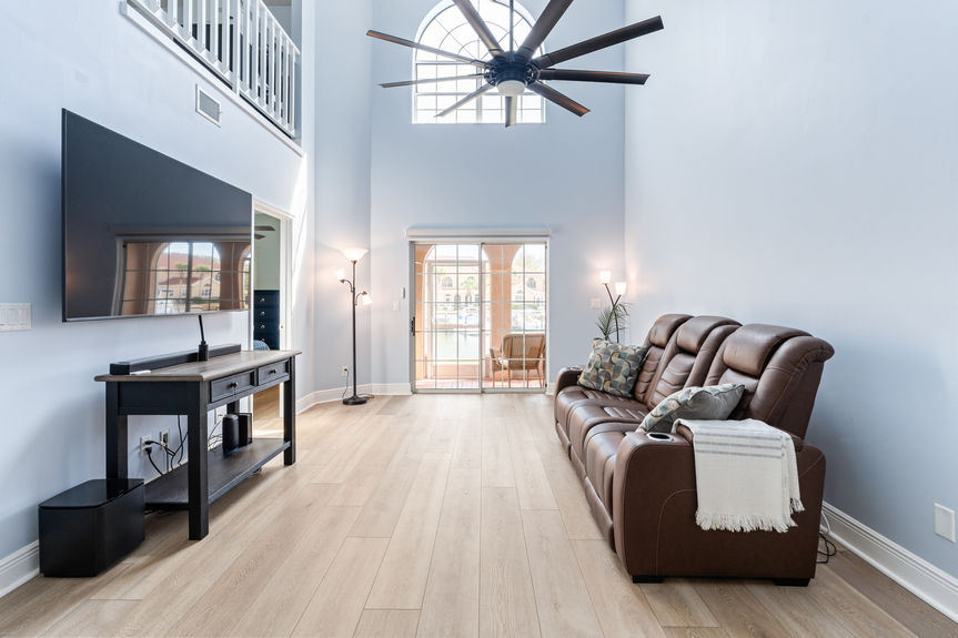 Open-concept living room with vaulted ceilings, a large modern black ceiling fan, and new flooring throughout the 37 Captains Walk condo.