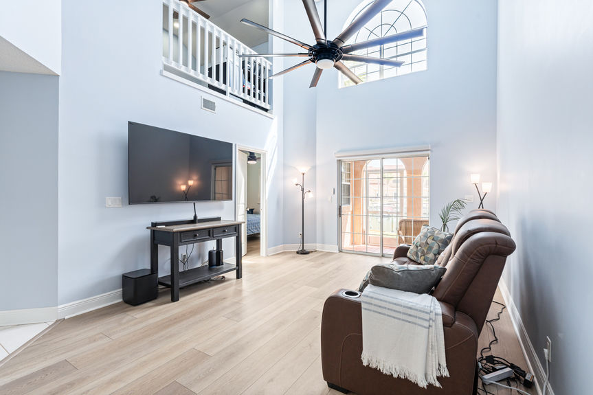 Open-concept living room with vaulted ceilings, a large modern black ceiling fan, and new flooring throughout the 37 Captains Walk condo.