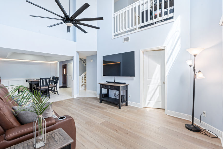 Open-concept living room with vaulted ceilings, a large modern black ceiling fan, and new flooring throughout the 37 Captains Walk condo.