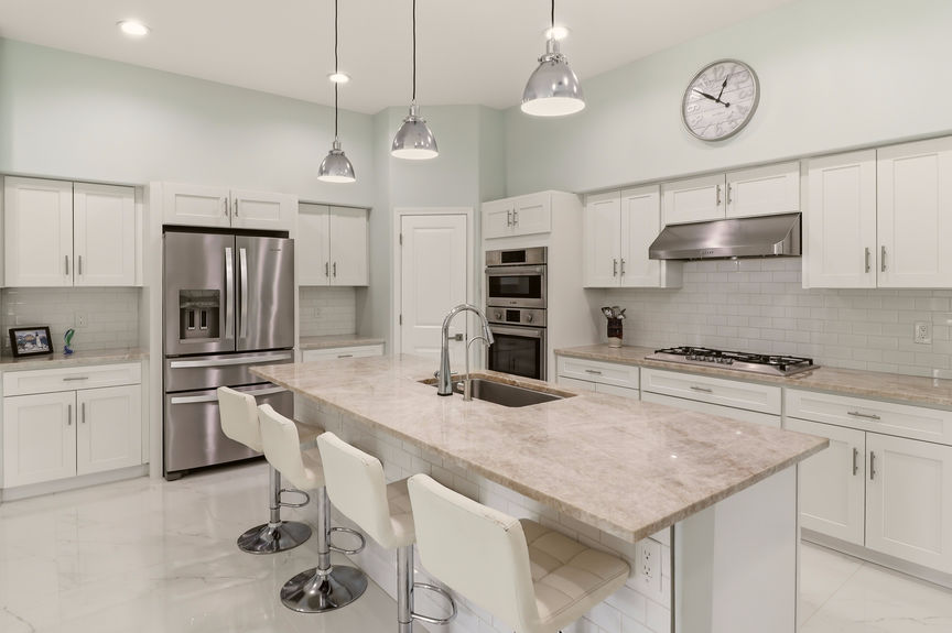 Modern kitchen at 5900 Costanero Road featuring white cabinets, stainless steel appliances, stone countertops, and a large center island with seating.