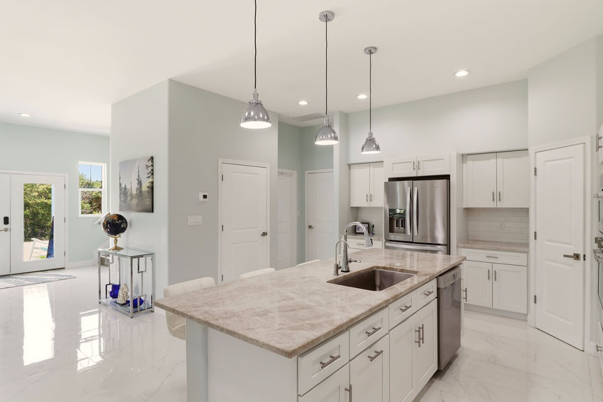 Modern kitchen at 5900 Costanero Road featuring white cabinets, stainless steel appliances, stone countertops, and a large center island with seating.