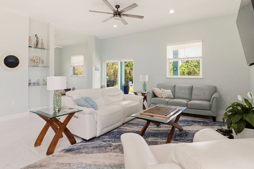 Wide shot of the living room at 5900 Costanero Road, St. Augustine, showing modern furniture, white tile flooring, and the open path to the kitchen.