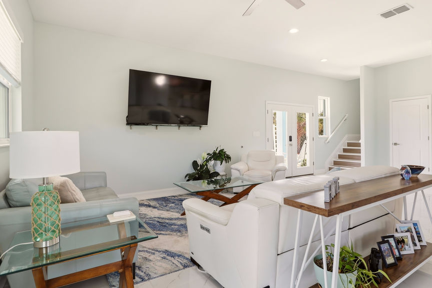 Wide shot of the living room at 5900 Costanero Road, St. Augustine, showing modern furniture, white tile flooring, and the open path to the kitchen.