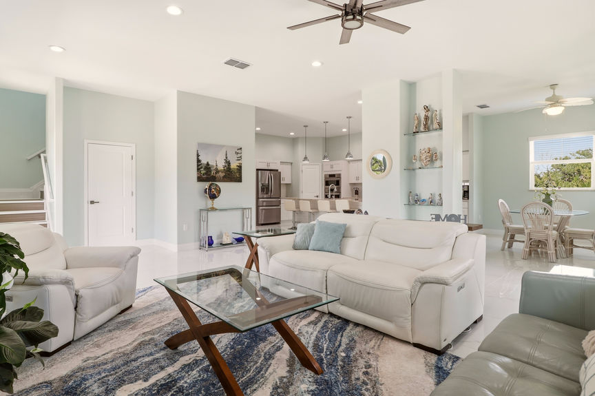 Wide shot of the living room at 5900 Costanero Road, St. Augustine, showing modern furniture, white tile flooring, and the open path to the kitchen.