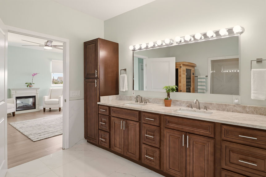 Master bathroom at 5900 Costanero Road featuring a large dark wood double vanity, stone countertops, and a view into the bedroom's fireplace area.