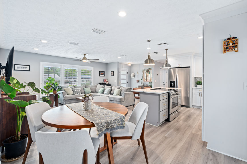 Spacious, light-filled living room featuring recessed lighting, a large sectional sofa, and a fluid layout connecting the main living areas to the kitchen.