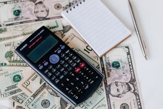 a calculator, pen, and notebook used for calculating finances