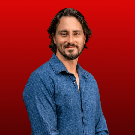 Dillon wearing blue dress shirt with a red backdrop
