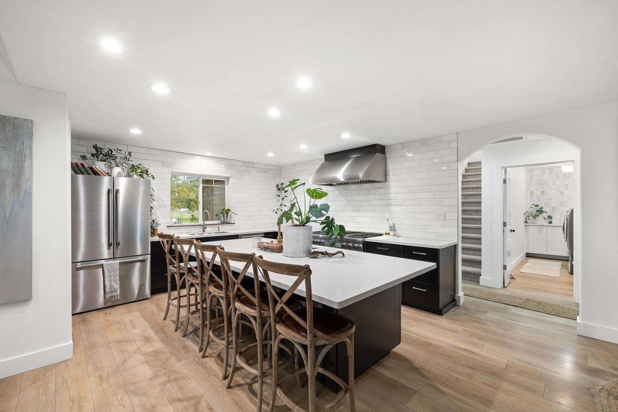 Modern farmhouse-style kitchen in a Selle Valley home sold by Elite Realty Partners by Real Broker in Sandpoint, Idaho. Features include a spacious quartz island, rustic wood barstools, stainless steel appliances, and subway tile backsplash
