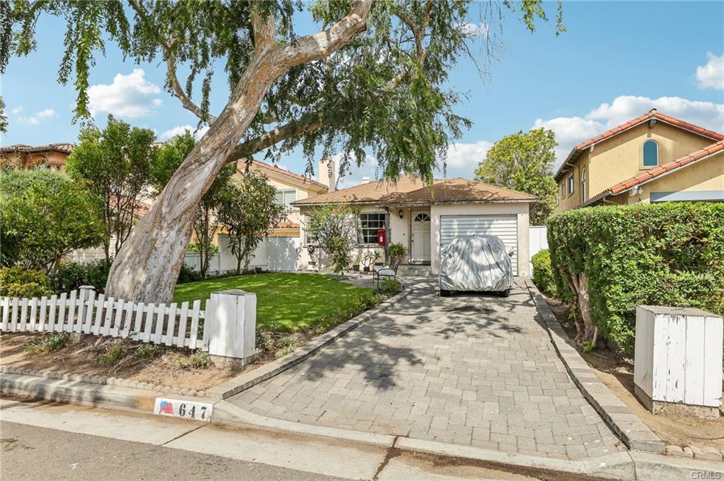 An older single-story South Bay home with a large tree and white picket fence, the kind of property often torn down to build a new home