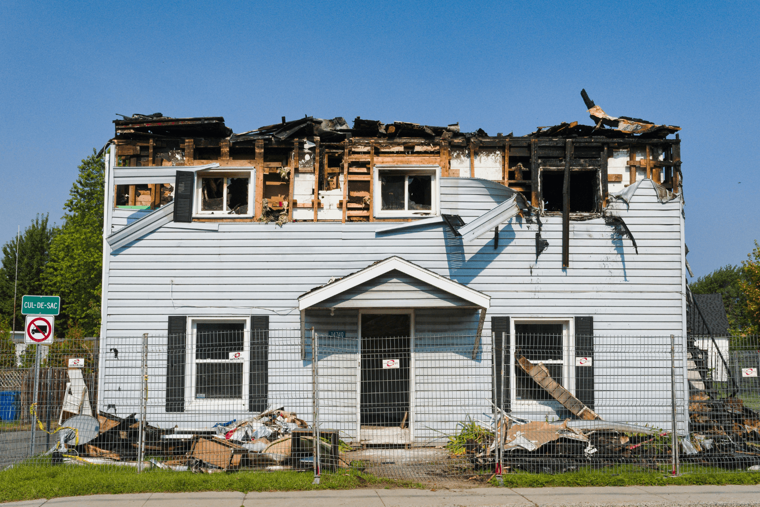 front of a fire damaged home with boarded windows