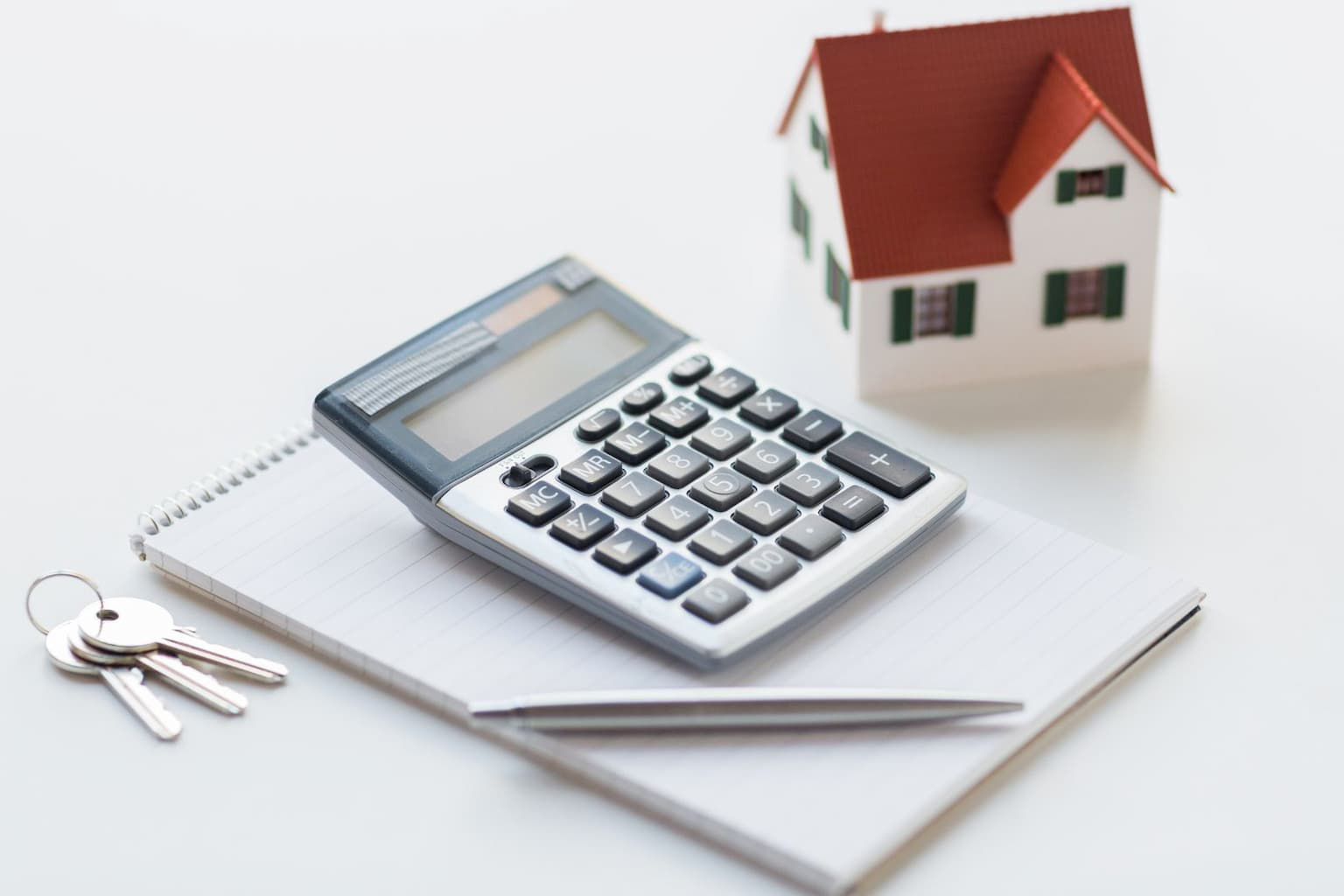 Calculator and house model on desk with financial papers