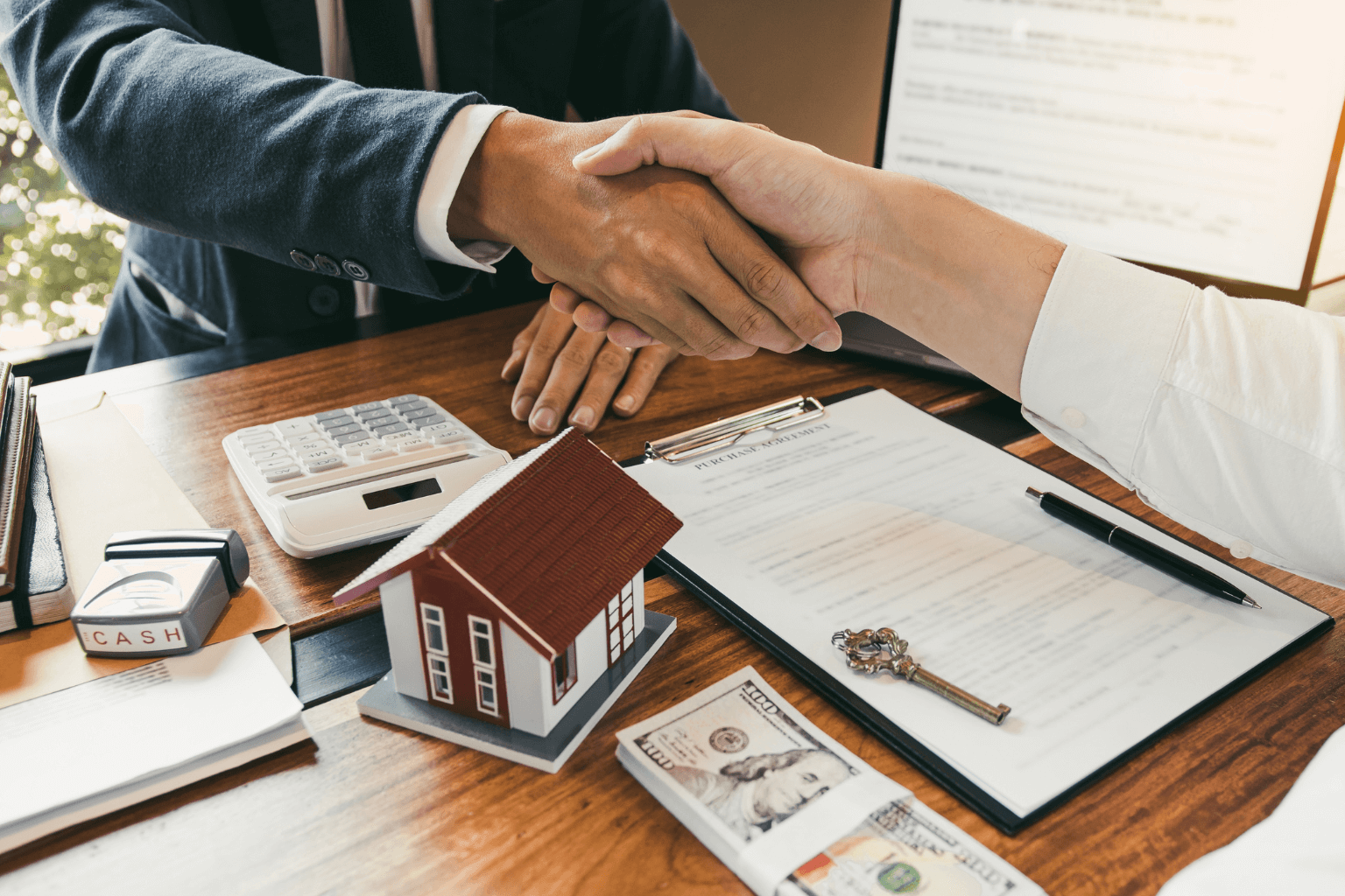 real estate agent and buyer shaking hands over a sales agreement