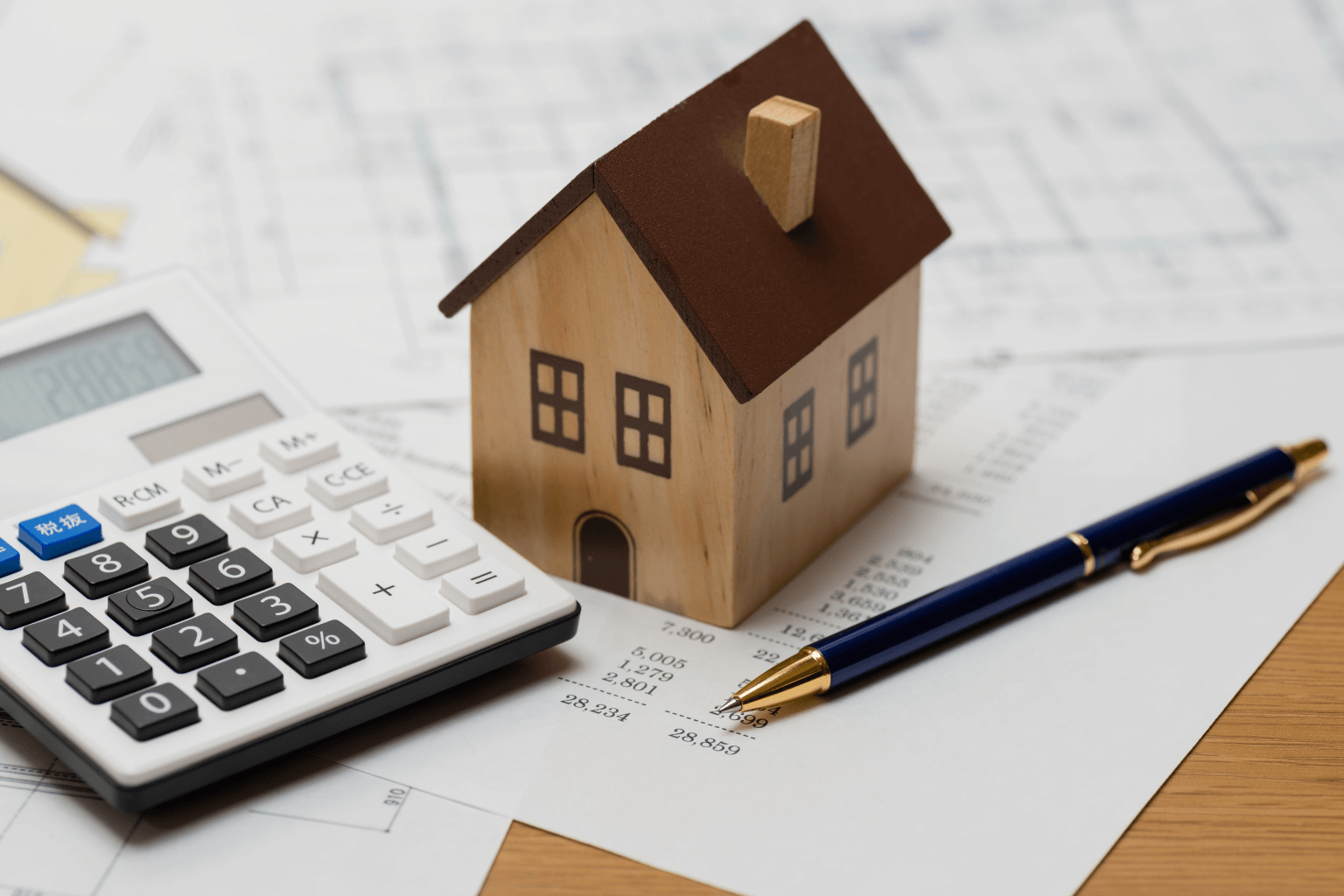 person using a calculator and house documents to estimate property value