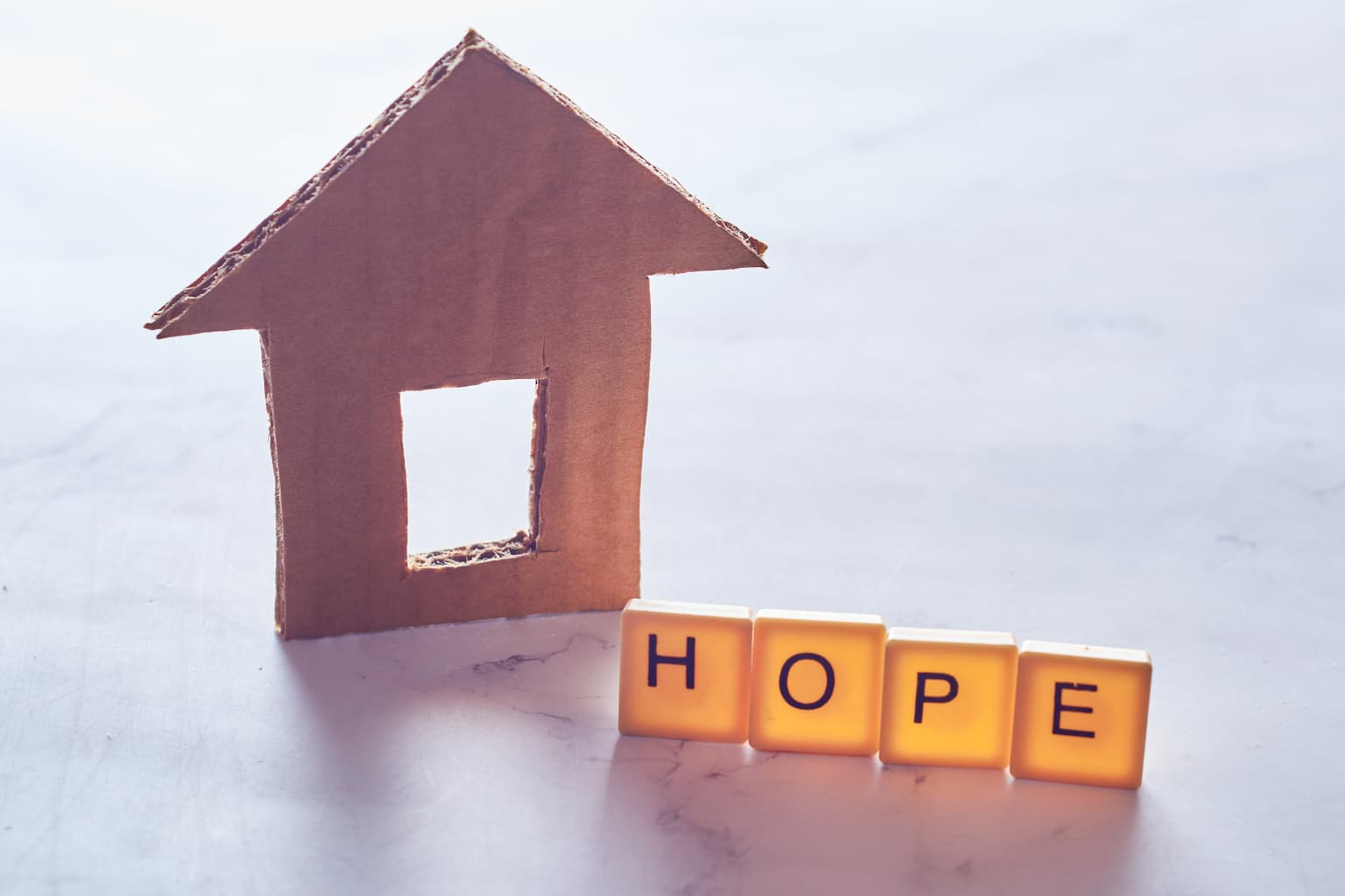 Paper house cutout beside the word HOPE on a table
