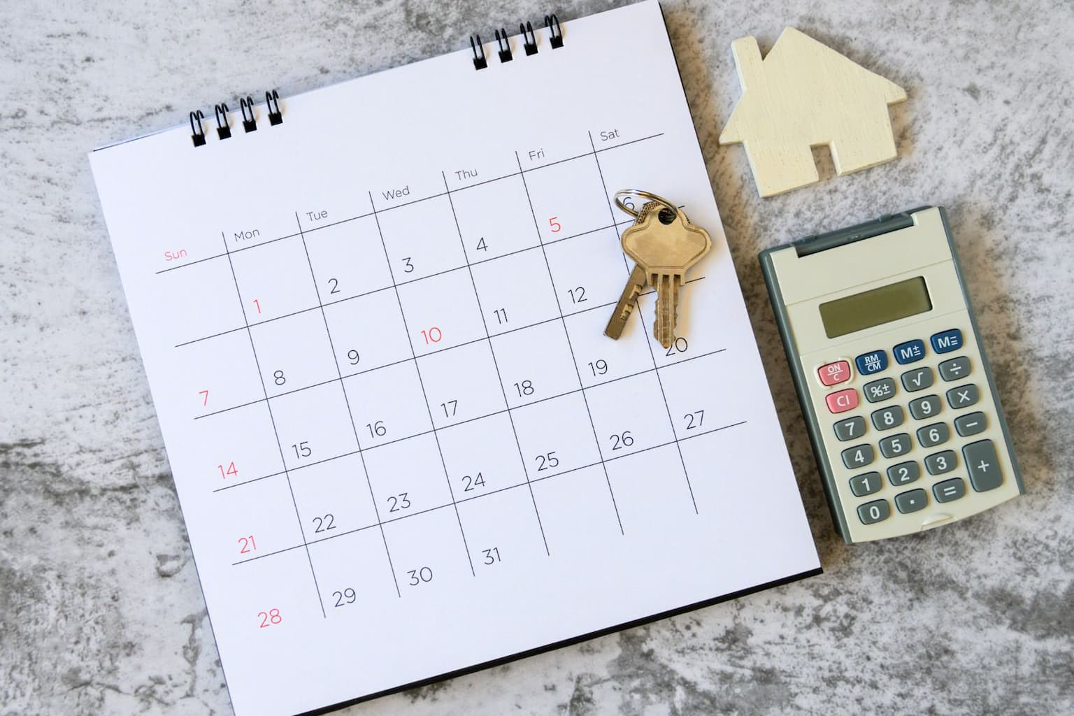 Calendar with house keys and calculator on table