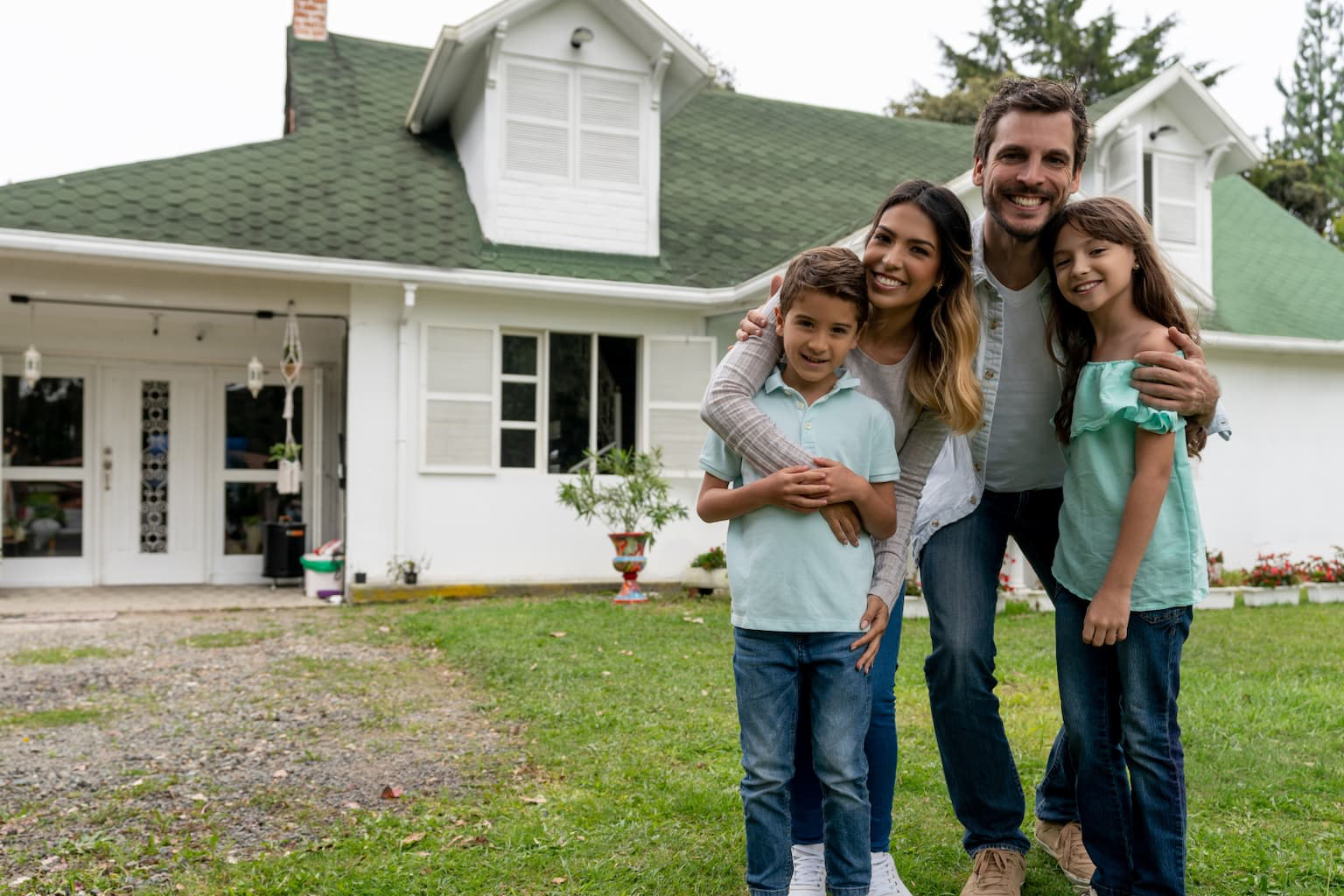 Happy family standing in front of their home after stopping foreclosure