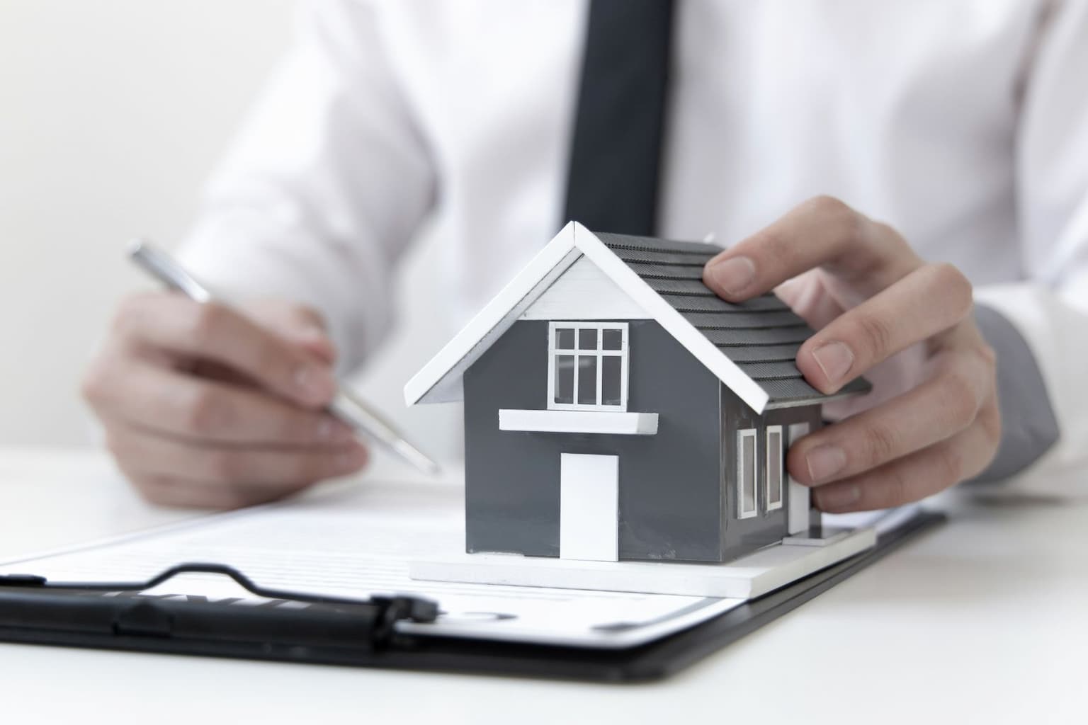 Person holding house model and overdue tax notice