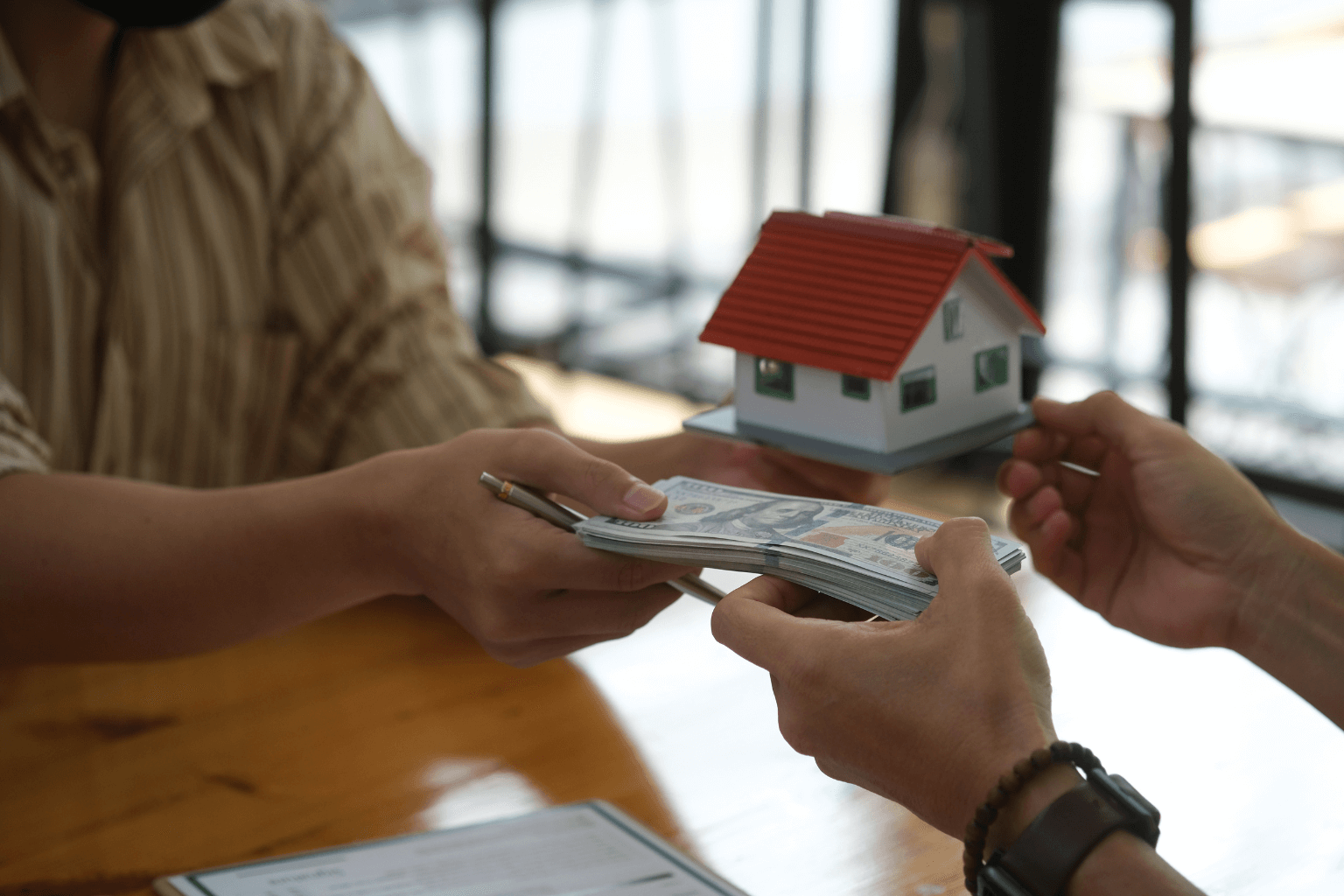 Person handing cash to another over a real estate contract