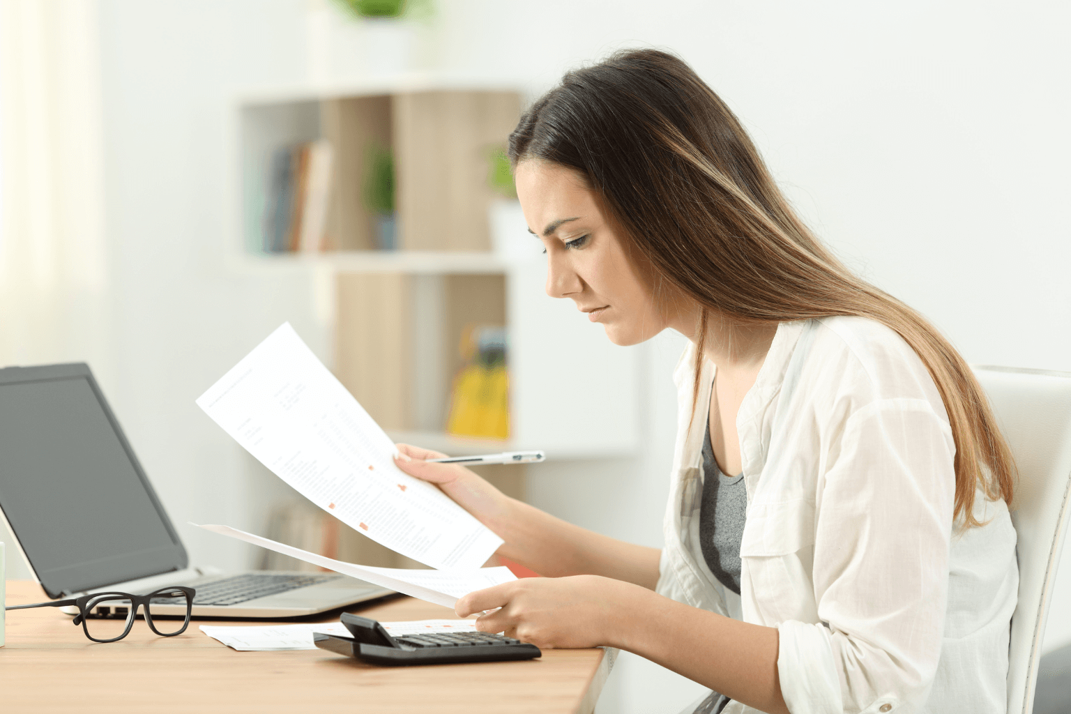 Person reviewing different house offers with calculator and papers