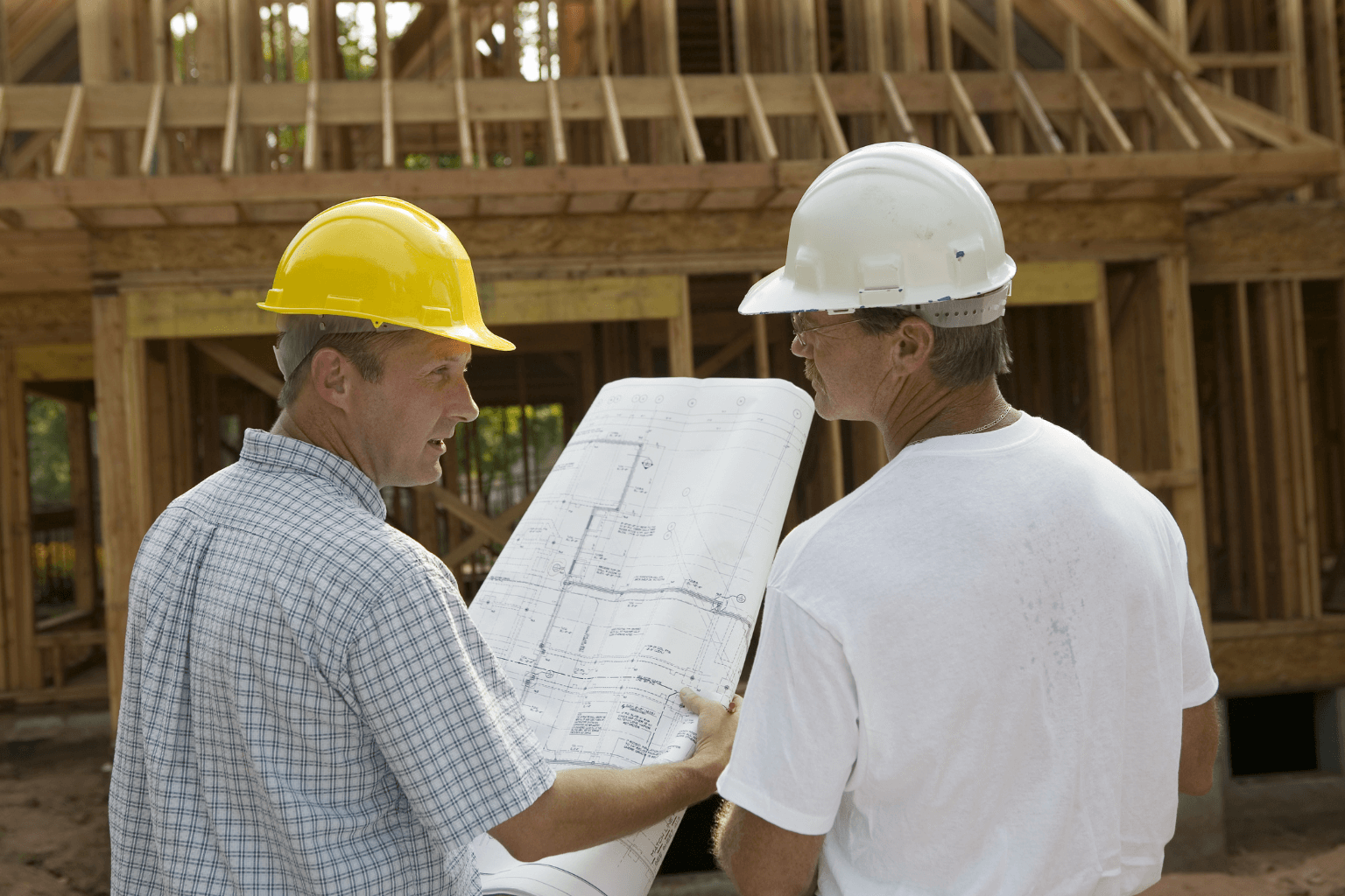 Contractor reviewing building plans at a worksite