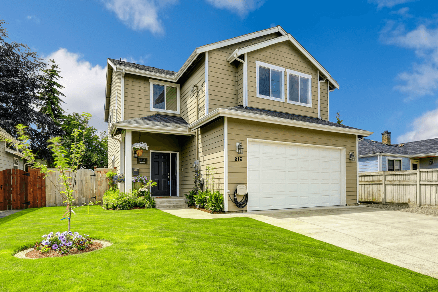 Front yard with trimmed lawn, flowers, and painted front door