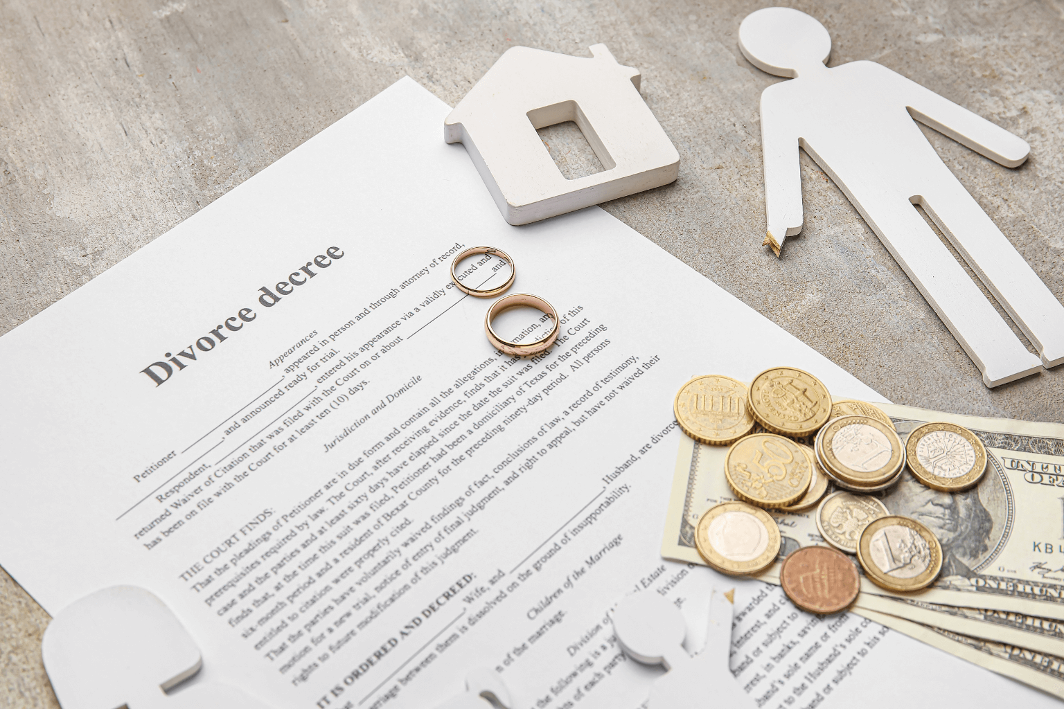 Divorce papers on table with house and couple cutouts and real money