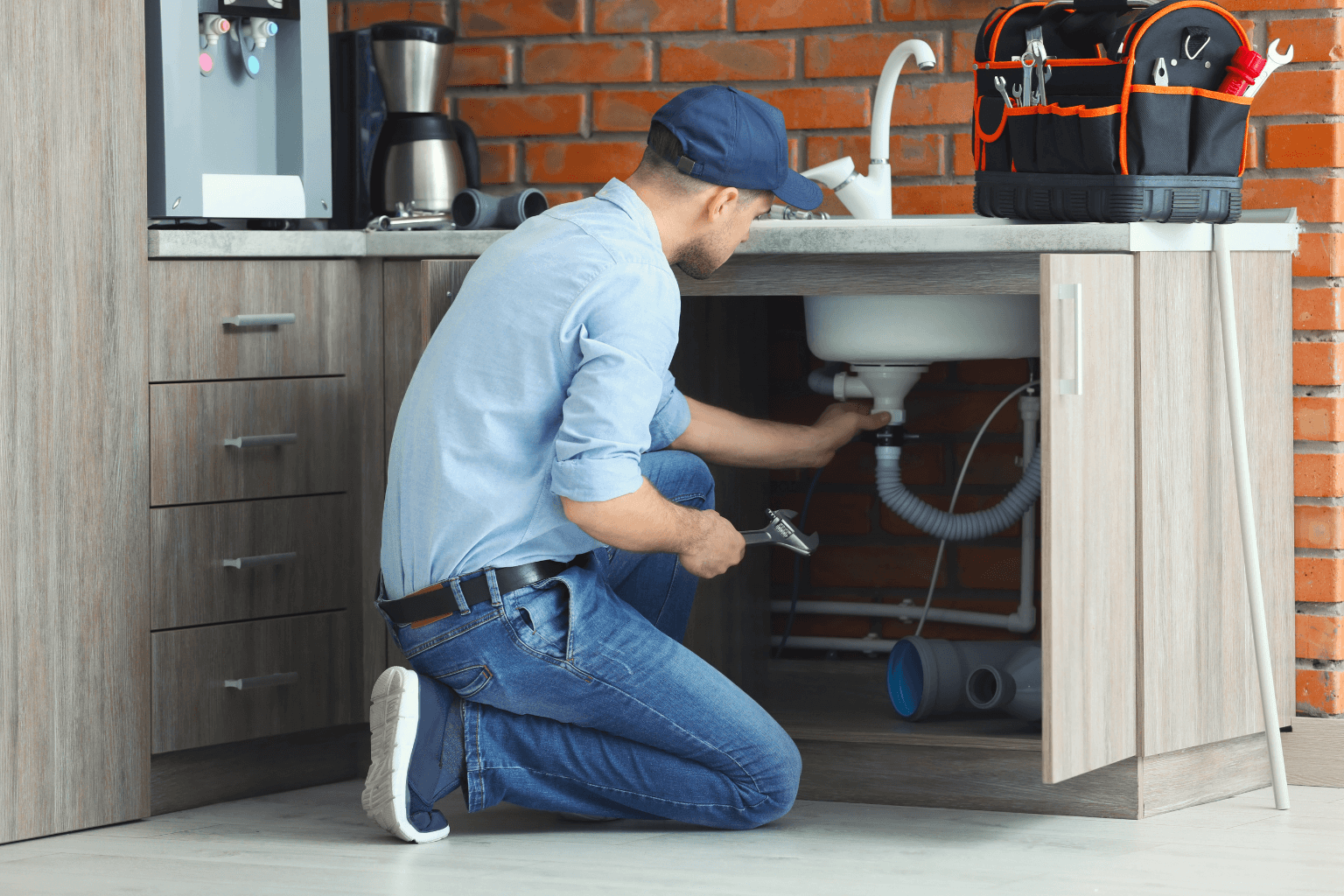 Worker repairing kitchen sink in rental home