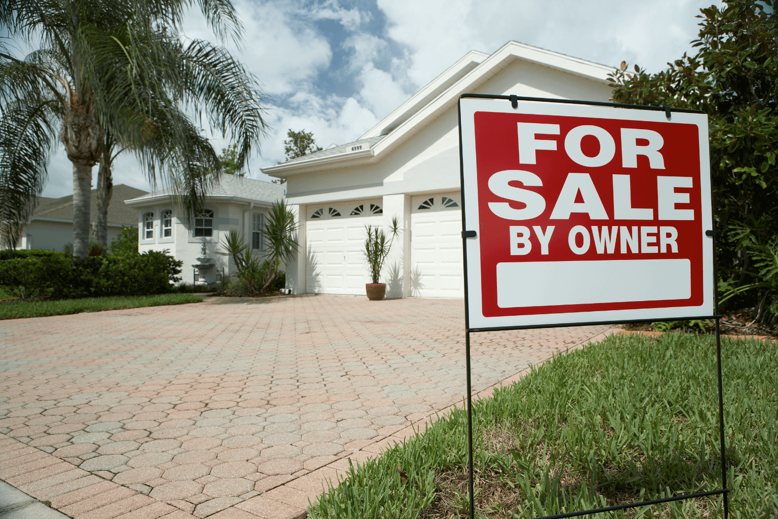 For Sale By Owner sign in front yard of a house